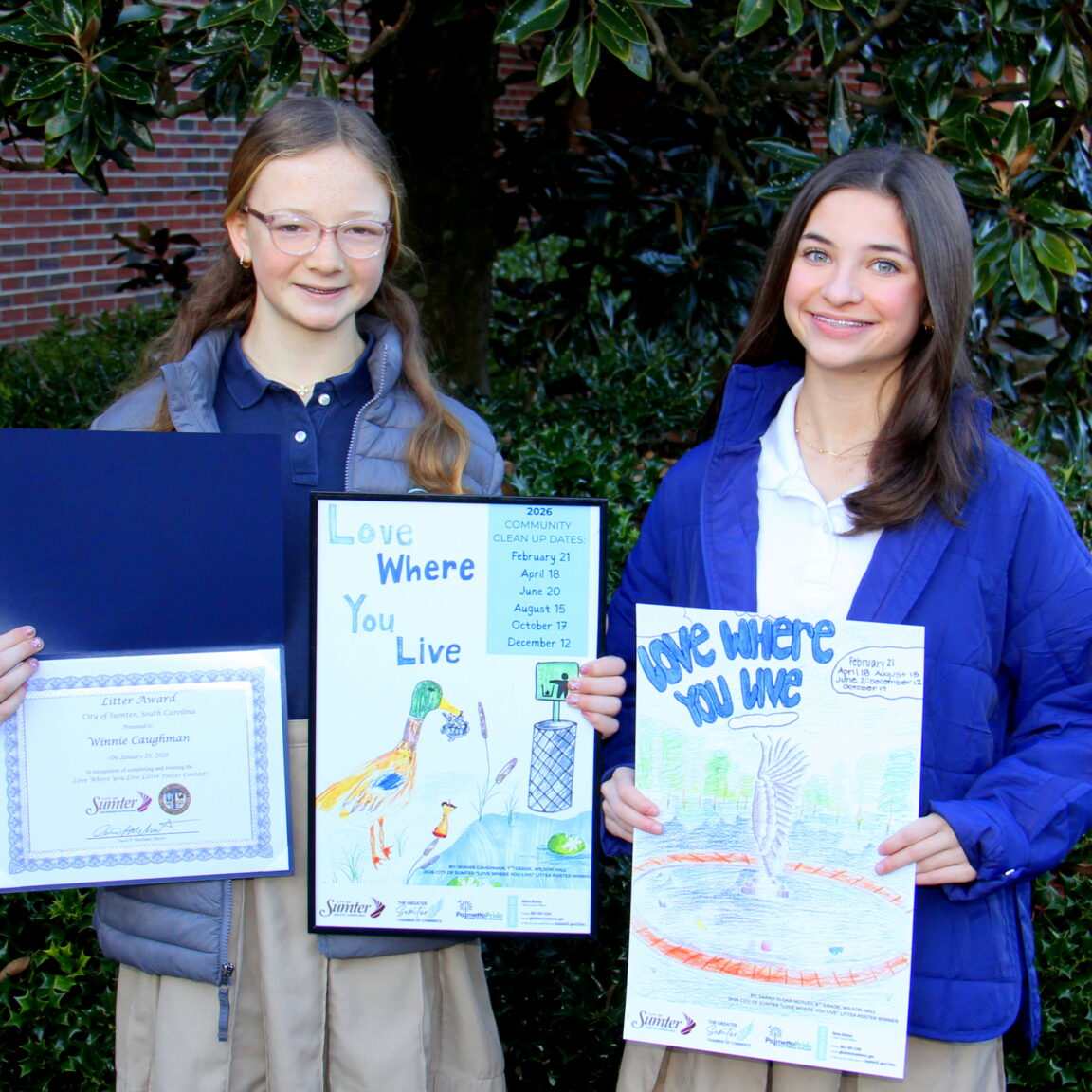 two students holding their winning poster artwork